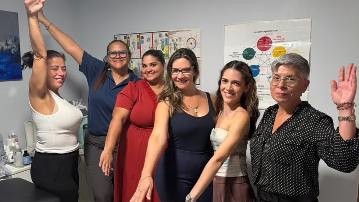 Participantes de un curso de Touch for Health con los brazos en alto